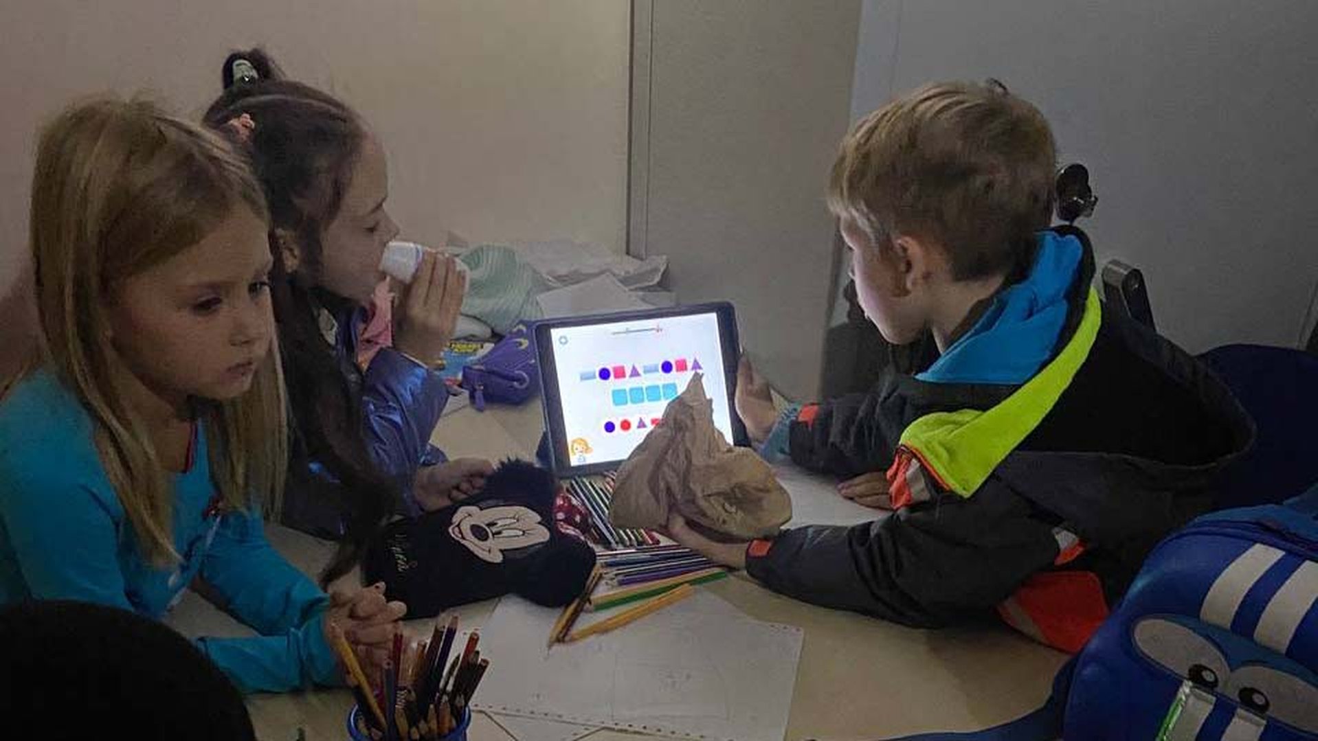 Three children in a bomb shelter in Ukraine using a tablet with Can't Wait to Learn, War Child's education app