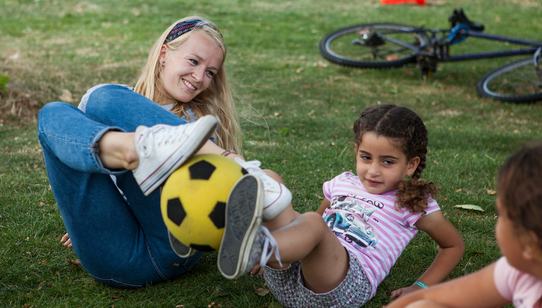 Vrijwilliger Lise geeft bal door aan kind tijdens TeamUp_War Child AZC Sneek_Nederland_180730