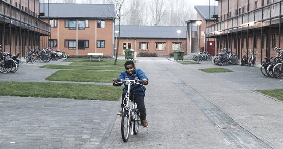 TeamUp jongen fietst over het terrein van azc asielzoekerscentrum Almere Stichting de Vrolijkheid_181206