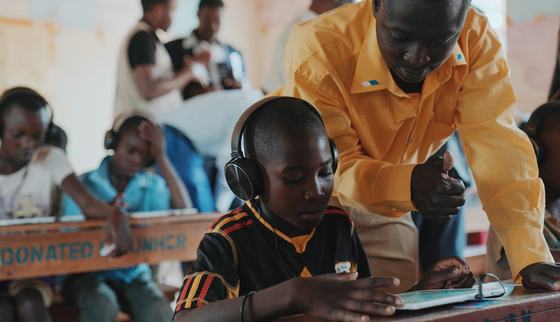 Teacher helping Roger using a tablet for Can't Wait to Learn_War Child Uganda_190918