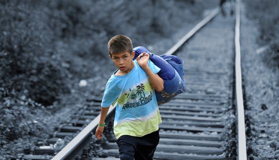 Jongen gevlucht met een tas spullen, lopend over het spoor_Tomislav Georgiev_War Child_19XXXX