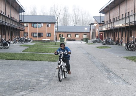 Een jongen fietst over het terrein van azc Almere credits Stichting de Vrolijkheid-Petra Katanic.jpg
