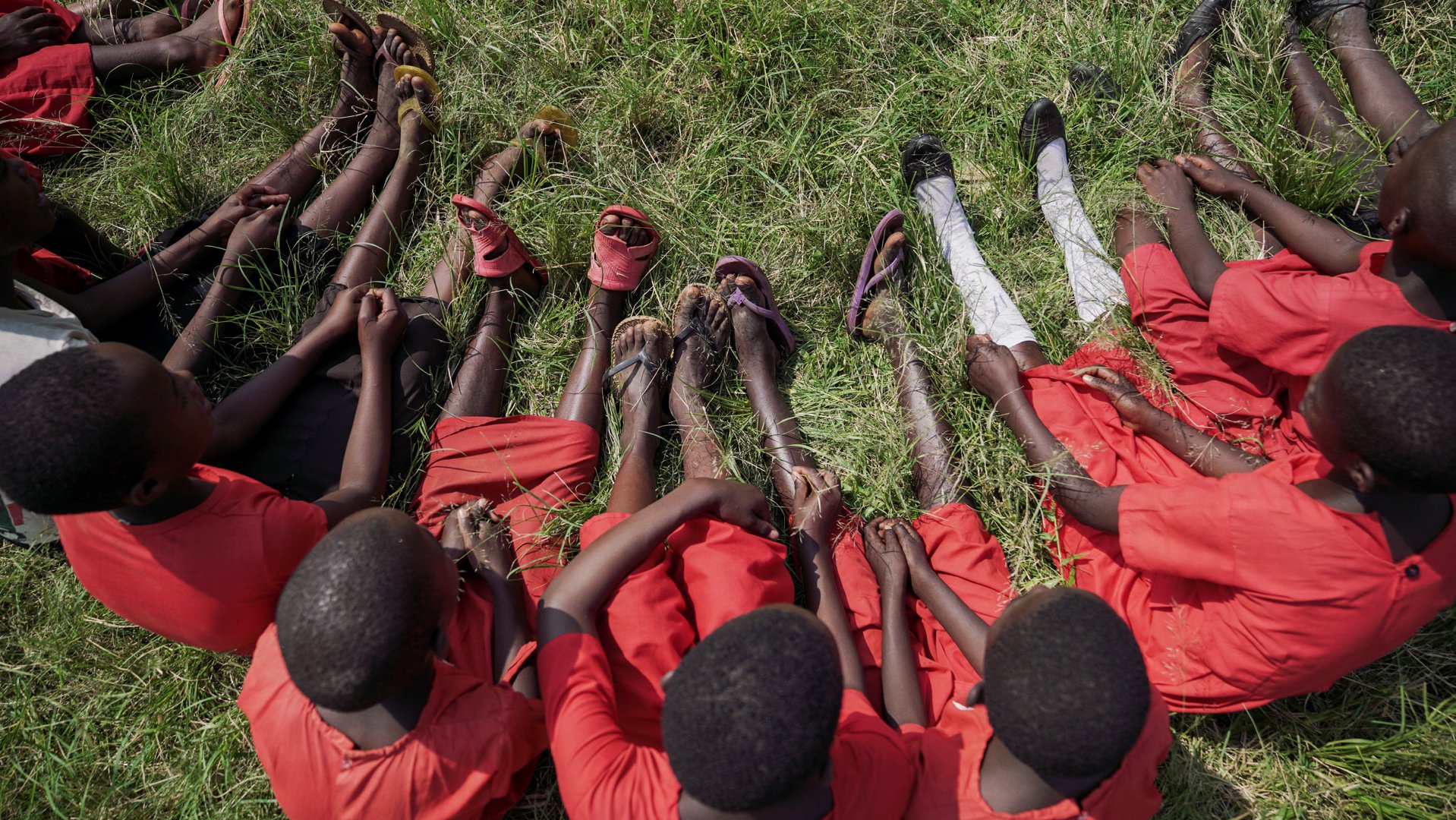 Kinderen in schooluniform in het gras - project War Child in Oeganda