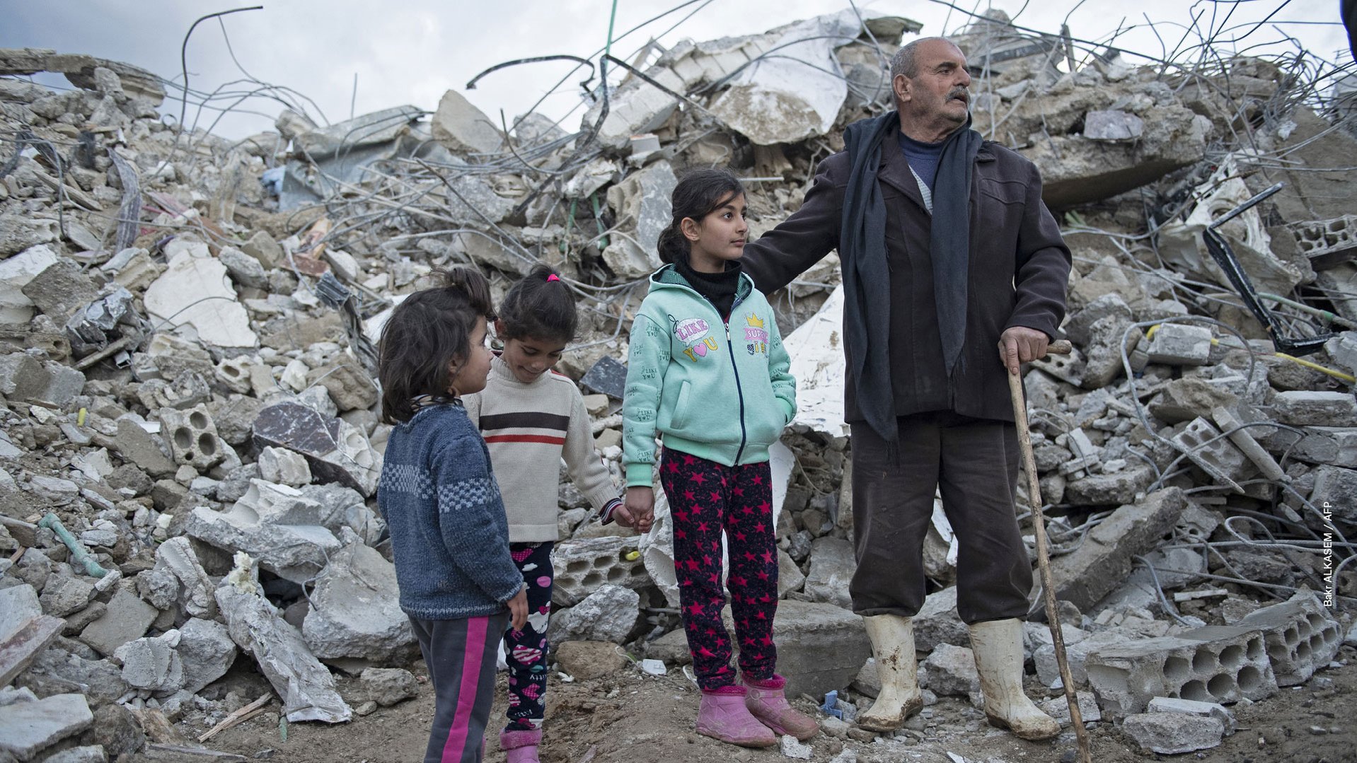 Een Syrische familie staat voor hun ingestorte huis