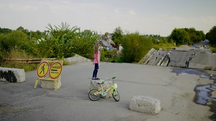 Natalya uit Oekraïne staat voor een gebombardeerde brug, vlakbij haar huis