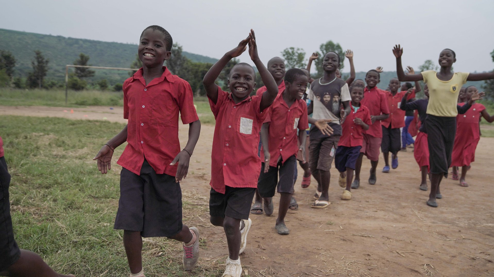 Schoolchildren in a line, with the teacher, joyfully raising their hands, clapping and smiling