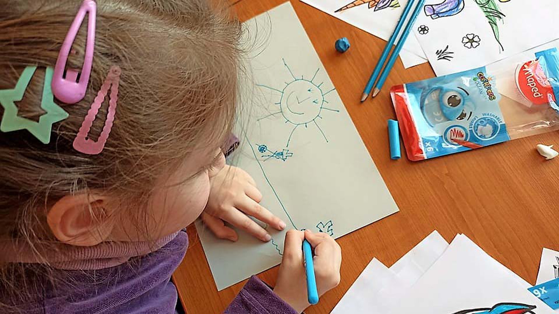 A young girl draws a sun. Children who fled Ukraine are drawing as part of psychological first aid.