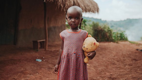 Girl Uganda with teddy bear in hands looking into the camera - War Child projects