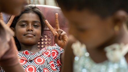 Meisje steekt vingers in de lucht vredesteken peace teken - War Child in Sri Lanka